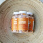 Close-up of Jellybee Turmeric & Ginger orange flavor gummies in a wooden bowl.